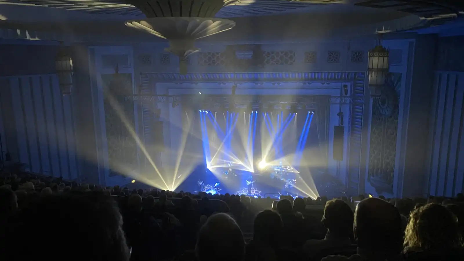 Blue and yellow beams over a stage and audience in a concert hall