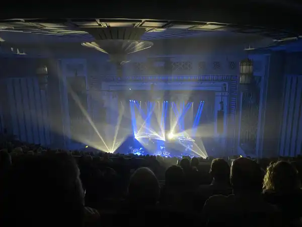 Blue and yellow beams over a stage and audience in a concert hall
