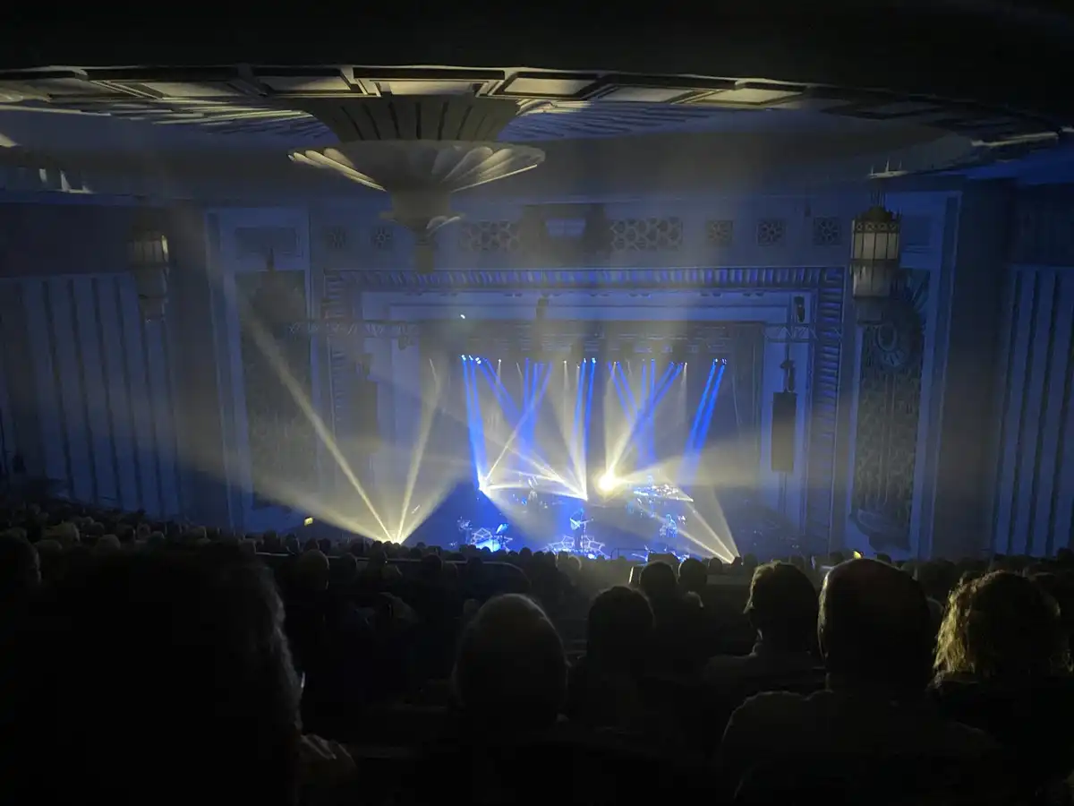 Blue and yellow beams over a stage and audience in a concert hall